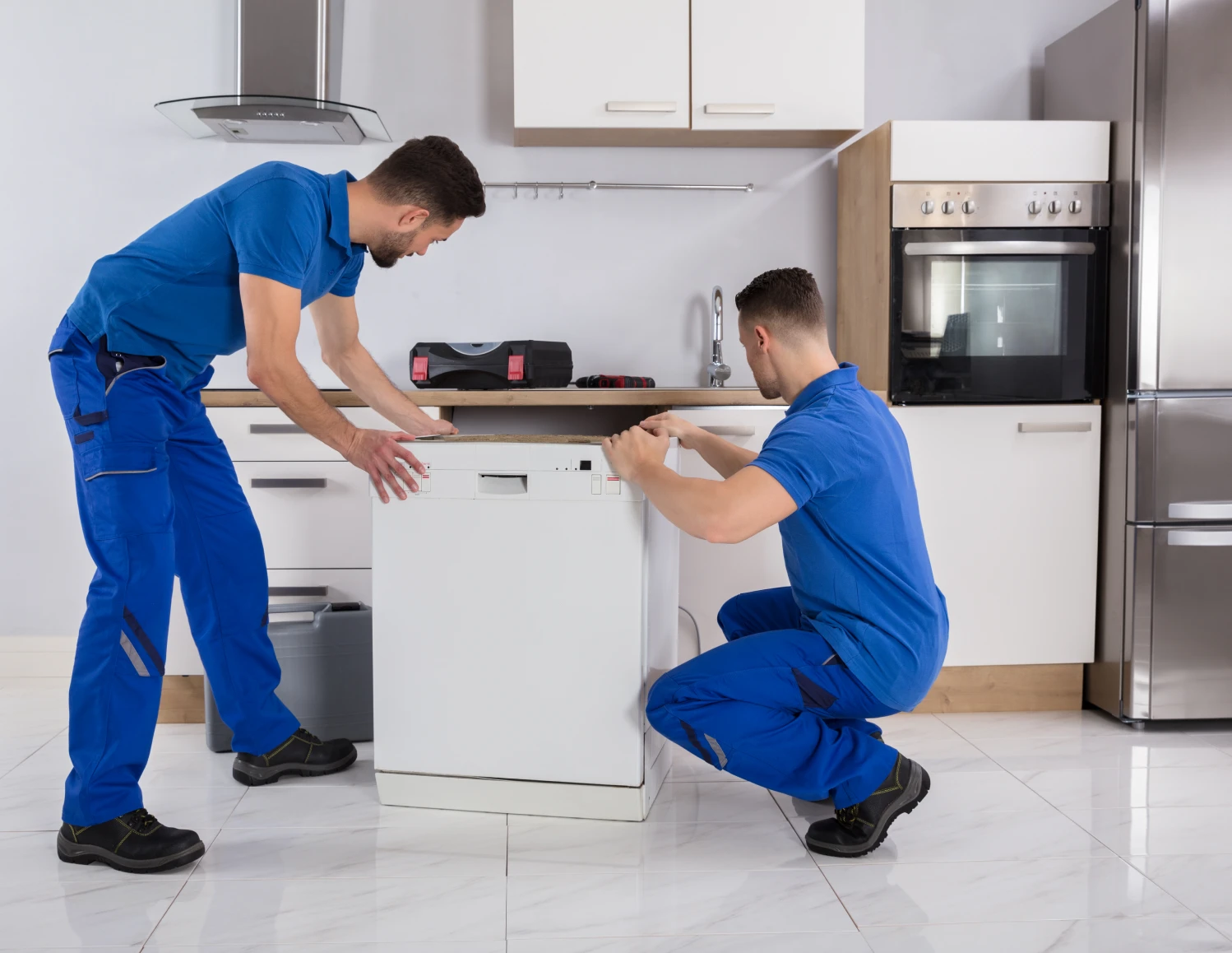 Technicians installing a dishwasher in kitchen.