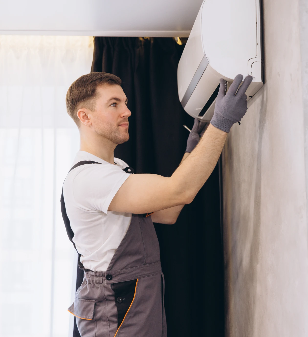 Technician installing a wall-mounted air conditioner.